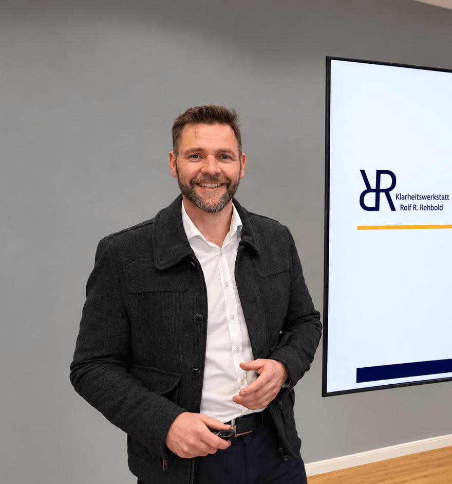 Rolf Rehbold, Gruender der Klarheitswerkstatt, im professionellen Portraet vor einer Praesentationswand